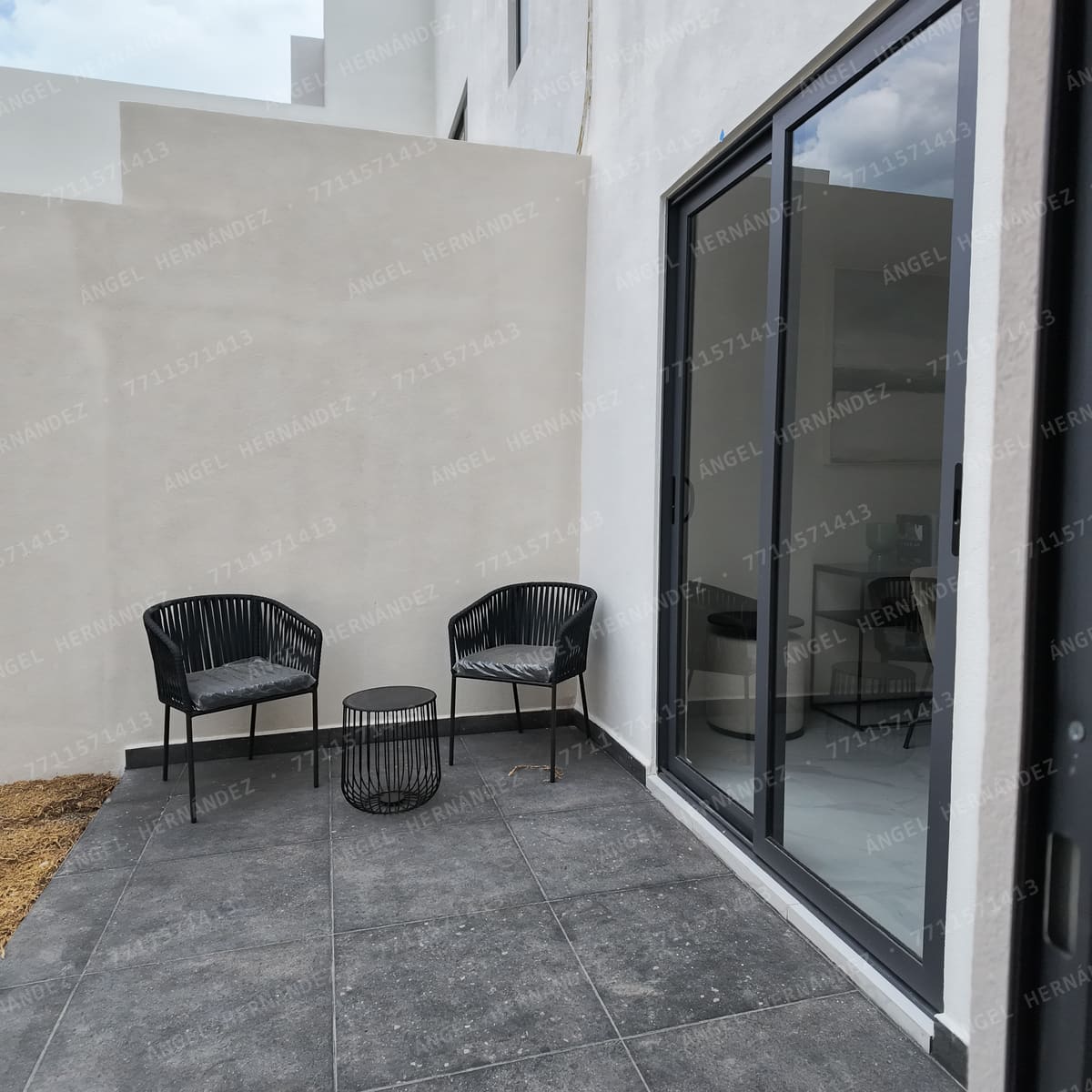 Patio con piso de piedra junto a la puerta corrediza del comedor en casa muestra Recinto, Basalto