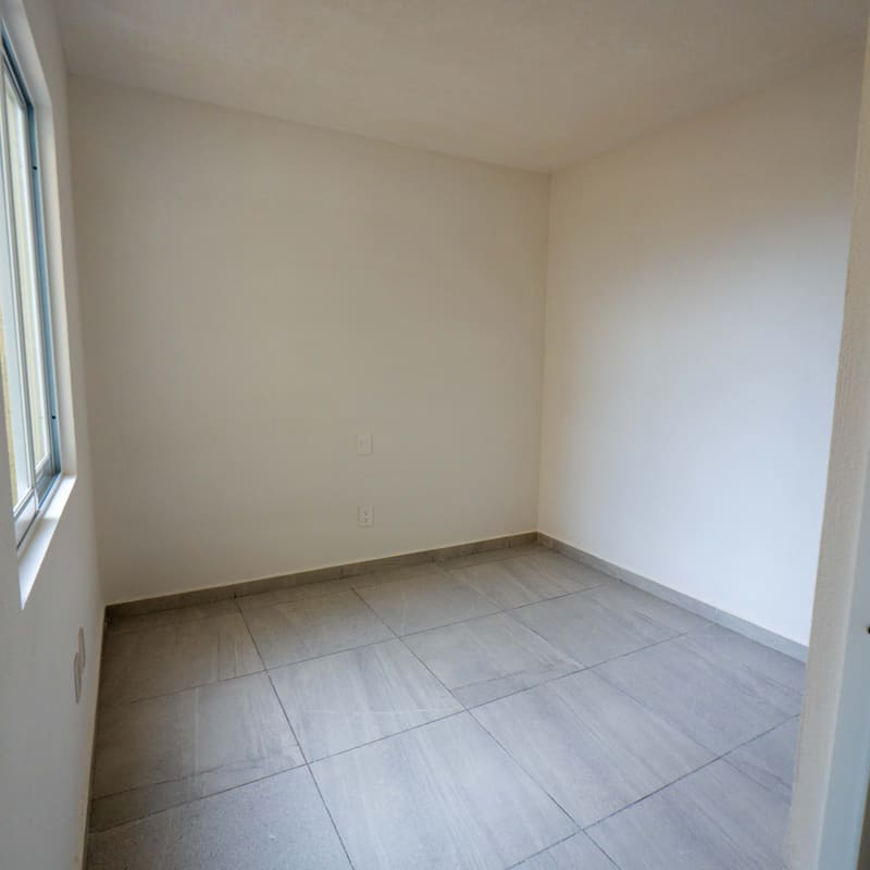 Recámara en planta baja con piso cerámico y ventana en modelo Málaga