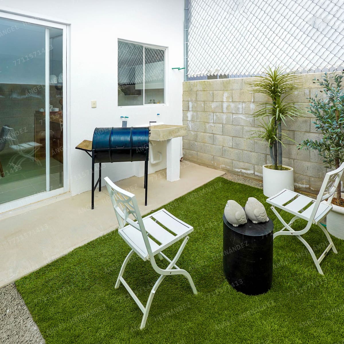 Patio trasero con asador y pasto sintético en casa muestra Marsella
