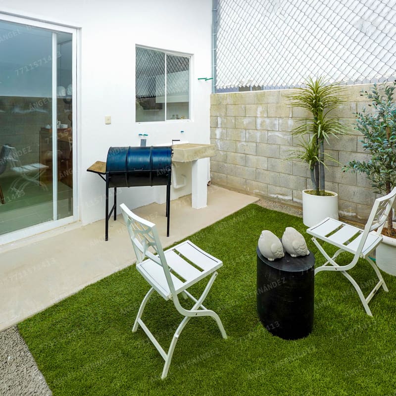 Patio trasero con asador y pasto sintético en casa muestra Marsella