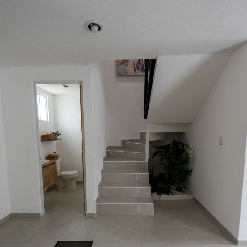 Escalera y acceso a medio baño en planta baja de modelo Niza